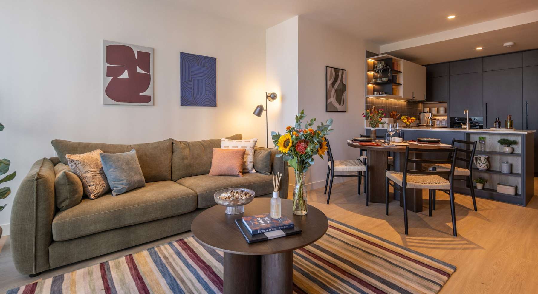 The living area of a two bedroom show apartment, with a sofa, armchairs and a dining table